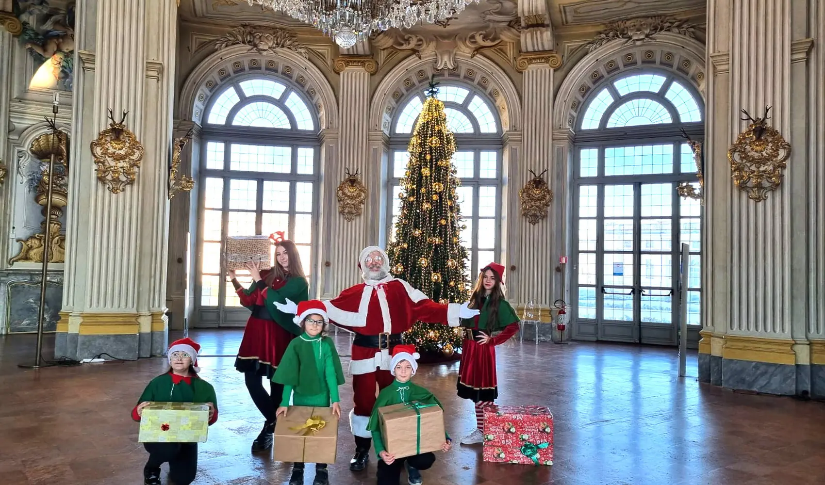 Babbo Natale con gli elfi nel salone della Palazzina, sotto il grande lampadario
