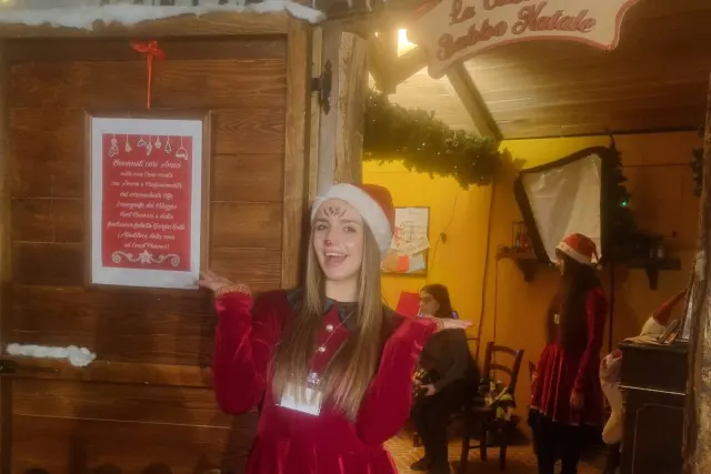 Un'elfa accoglie i visitatori davanti alla baita di Babbo Natale